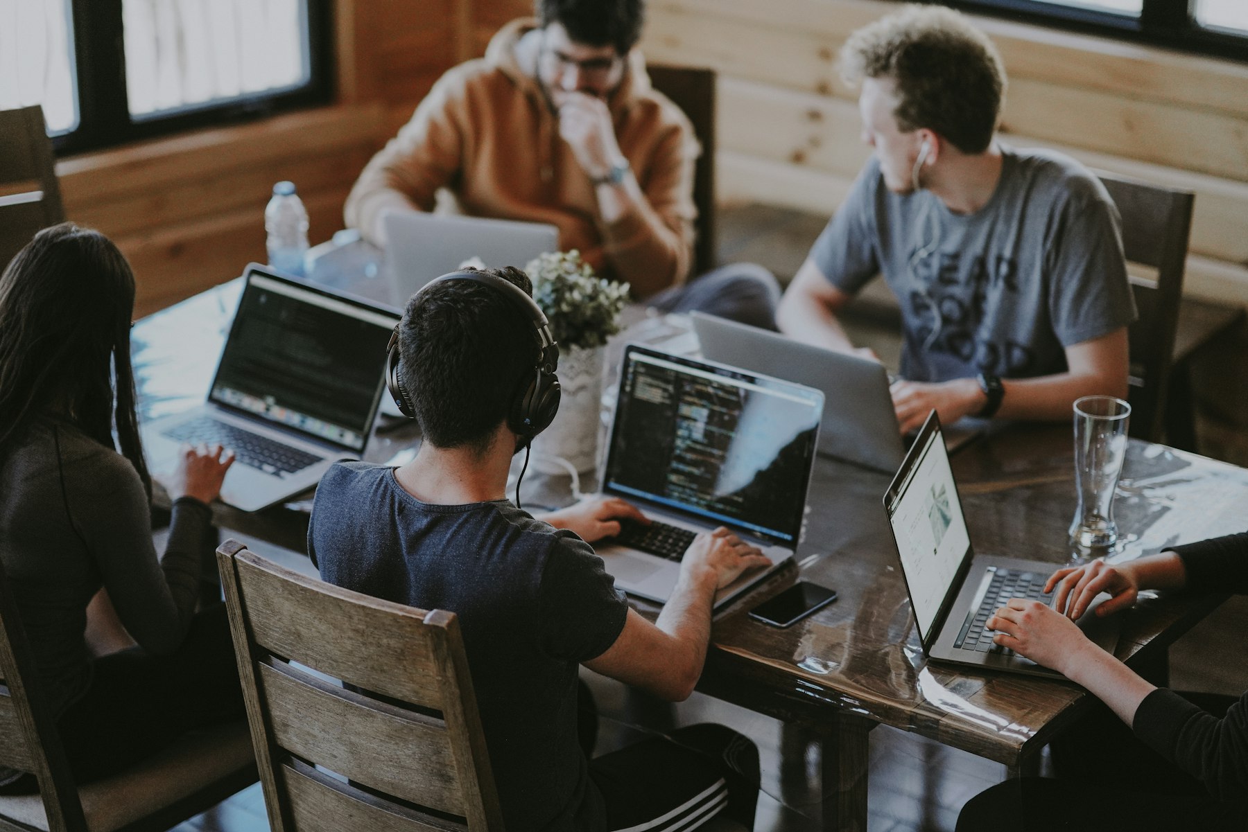 Several people working on laptops around a shared wooden table