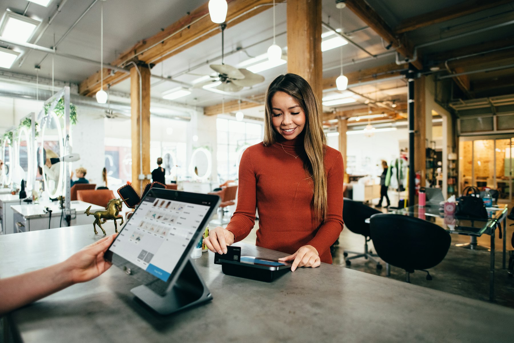 A small business owner smiling while serving a customer at a shop counter