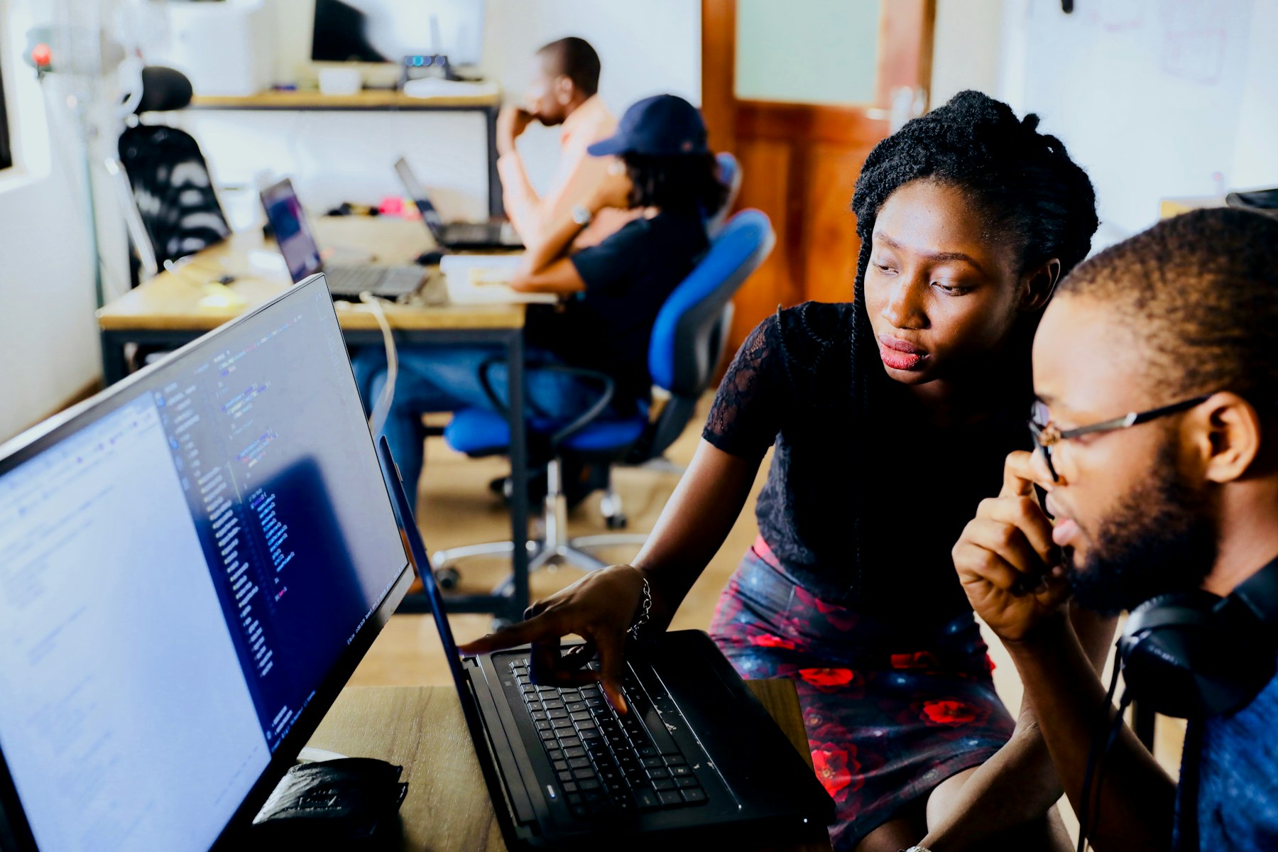 Two colleagues studying data on a laptop screen in an office